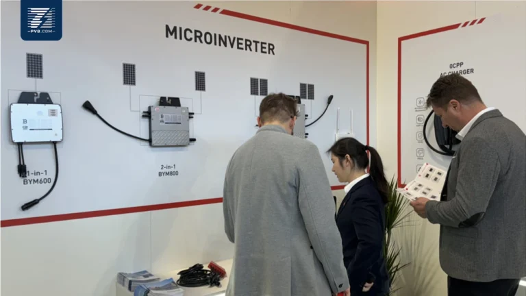 Microinverter display at a trade show booth with people examining the products.