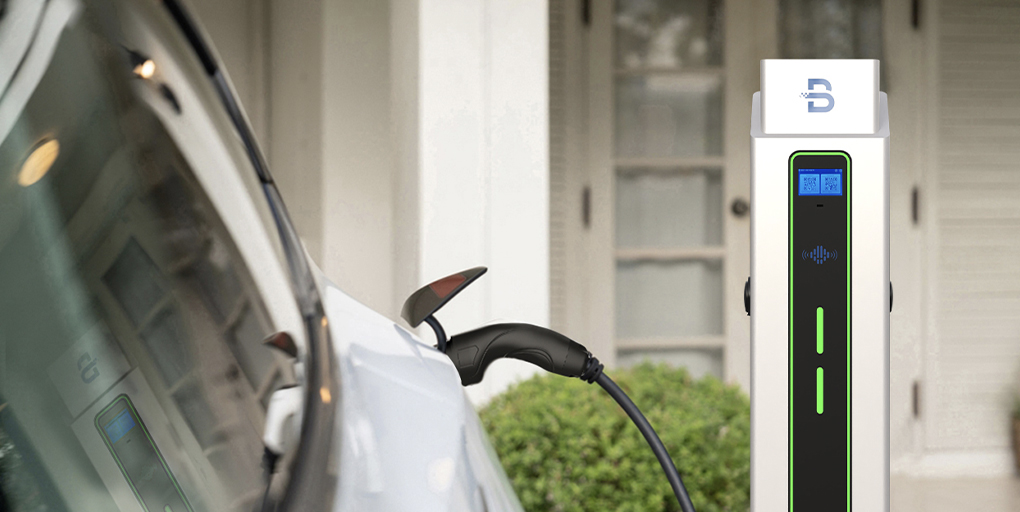 Electric vehicle charging station installed on the wall of a modern house with a blue car parked in front.